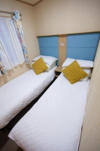 Duas camas num pequeno quarto com uma janela em Caravan by Camber Sands 2 em Camber