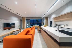 Villa Milo في سيدي: غرفة معيشة مع أريكة برتقالية ومطبخ