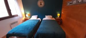 two beds in a room with blue walls and two lamps at Chalet de l'Ours Brun, gîte 3 étoiles in Gère-Belesten