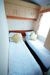 duas camas num pequeno quarto num barco em Caravan by Camber Sands em Camber