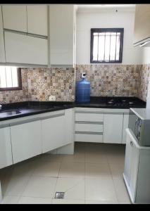 una cocina con armarios blancos y un jarrón azul en la encimera en Guarujá enseada sp, en Guarujá