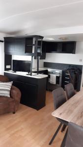 een keuken met zwarte kasten en een tafel met stoelen bij Mobil-Home 6 Personnes in Saint-Pair-sur-Mer