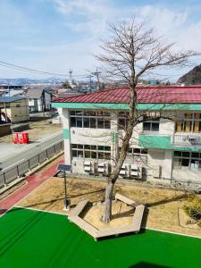 un edificio con un árbol delante de un edificio en Yamagata Guesthouse山形ゲストハウス, en Murayama