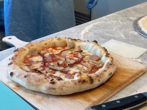 a pizza sitting on top of a wooden cutting board at Yamagata Guesthouse山形ゲストハウス in Murayama