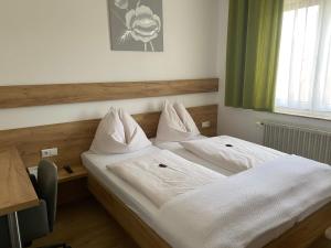two twin beds in a room with a window at Pension Kinzl in Offenhausen