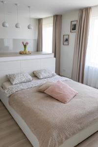 uma cama branca com uma almofada rosa em cima em Harmony em Jelgava