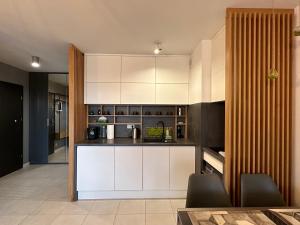 a kitchen with white cabinets and black counters at AHAVA APARTMENTS in Kołobrzeg