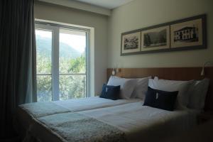 a bedroom with a bed with a large window at Hotel da Vila in Manteigas