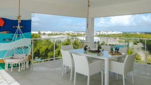 uma sala de jantar com uma mesa e cadeiras brancas e janelas grandes em Beach View PH Jacuzzi in Hard Rock Golf em Punta Cana