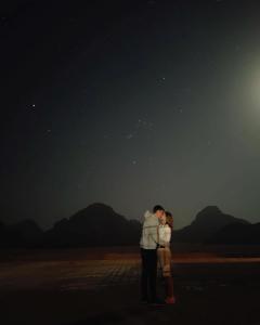 a man and a woman kissing under the night sky at stars magic camp in Wadi Rum