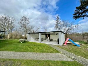 un pequeño edificio blanco con parque infantil y tobogán en Cosy holiday home with pet friendly garden en Elsendorp
