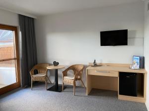 Zimmer mit einem Schreibtisch, einem Tisch und Stühlen in der Unterkunft Andreashof Mörbisch in Mörbisch am See