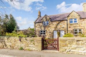 an old stone house with a wooden gate at Miller's Retreat in Alnwick