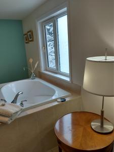 baño con bañera, mesa y lámpara en By the Bay Lavender Villa, en Chemainus