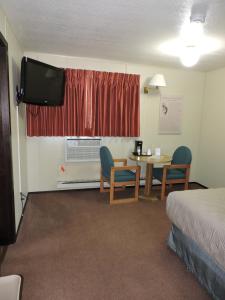 Cette chambre comprend un lit, une table et une télévision. dans l'établissement Kokopelli Inn, à Bluff