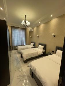 Cette chambre comprend 3 lits et un lustre. dans l'établissement VİP COTTAGE, à Qabala