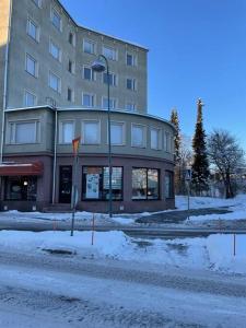 budynek na śnieżnej ulicy przed budynkiem w obiekcie The Park House Suite, Jakobstad w mieście Jakobstad