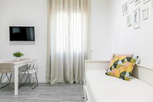a white bedroom with a bed and a table and a television at Appartamento La Fortezza in Milan