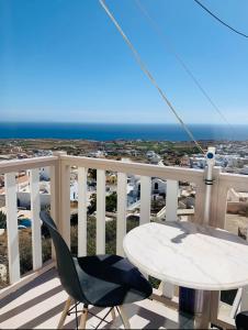 a table and a chair on a balcony with the ocean at Lefteris Traditional Rooms in Fira