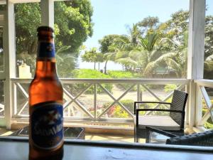 una botella de cerveza sentada en una mesa frente a una ventana en Serenity Beach Cottages en Utila
