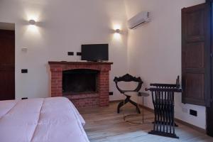 um quarto com uma cama e uma lareira com uma televisão em Tenuta Luogo Marchese em Pollina