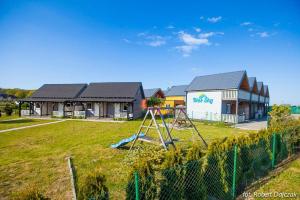 a yard with a playground in front of a building at Domki Letniskowe Blue Sky 1 in Rewal
