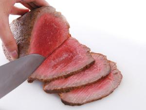 una persona cortando un trozo de carne con un cuchillo en APA Hotel Shinjuku-Kabukicho Tower, en Tokio