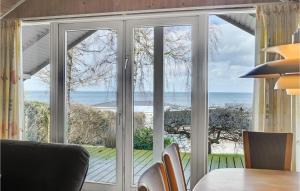 a dining room with sliding glass doors looking out at the ocean at Holiday Home Kystvejen Køge Ix in Valløby +17 photos