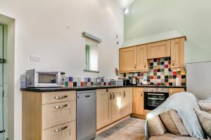 a kitchen with wooden cabinets and a microwave at No 1 The Granary in Llangefni