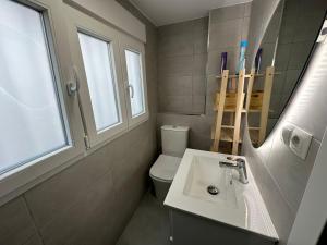 een badkamer met een wastafel, een toilet en een spiegel bij Casa Quintero Valencia Playa Cabañal in Valencia