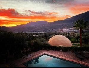 una piscina con tenda di fronte al tramonto di Cortijo Tayula-Centro de Recuperación y Descanso a Granada
