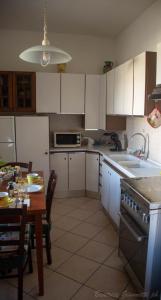 uma cozinha com armários brancos, uma mesa e um lavatório em Appartamento per Vacanze Domus Lunae em Luni
