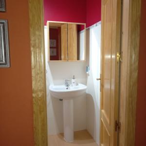 uma casa de banho com um lavatório branco e um espelho. em ADOSADO FAMILIAR em Huelva