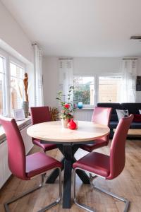 a dining room with a table and red chairs at FH Ostfriesland to Huus, zw. Emden und Greetsiel in Hinte