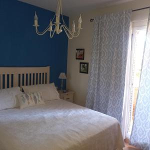 a bedroom with a large bed and a chandelier at ADOSADO FAMILIAR in Huelva
