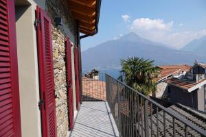 a balcony with red doors and a view of a mountain at Casale Bella.Vista in Pianello Del Lario