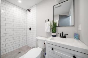 La salle de bains blanche est pourvue d'un lavabo et d'un miroir. dans l'établissement 4BR 1BH Apt in South Boston near Old Harbor Beach, à Boston