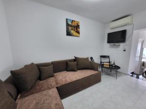 a living room with a brown couch and a tv at Apartman Dora with sea view and terrace in Umag