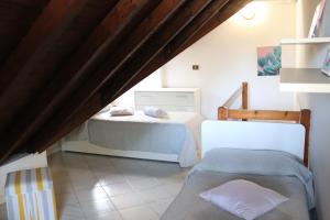 Pokój na poddaszu z 2 łóżkami i krzesłem w obiekcie Beach House Riviera w Lignano Sabbiadoro