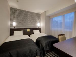 um quarto com 2 camas, uma mesa e uma janela em APA Hotel Shinjuku-Kabukicho Tower em Tóquio