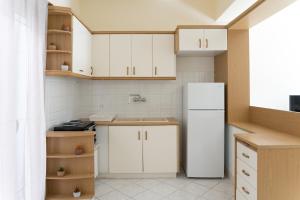 een keuken met witte kasten en een witte koelkast bij Foto's apartment in Lixouri