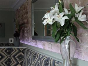 Parkside Hotel في Cleator: مزهرية من الزهور البيضاء تقف على طاولة أمام المرآة