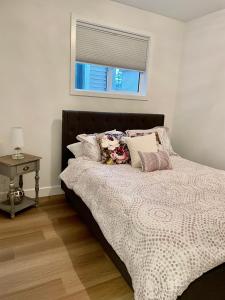 a bed with pillows and a window in a bedroom at Adorable 1 Bedroom Suite- a skip to Galloping Goose in Victoria