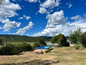 a house with a swimming pool next to a lake at Punta Sur - Dique Cabra Corral in Coronel Moldes