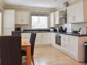 a kitchen with white cabinets and a wooden table at The Lodge in Cosham