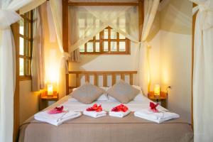 een slaapkamer met een bed met rode bogen op de kussens bij Hotel Casa Merlin in Puerto Viejo