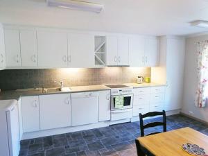 una cocina con armarios blancos y una mesa con una silla en Charming house by the sea, Lofoten!, en Laupstad