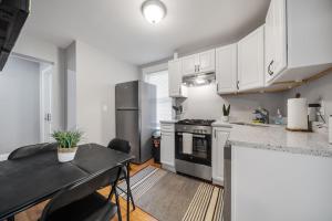 uma cozinha com armários brancos e um forno de fogão preto em 4BR1BTH South Boston Apt perfect for commutes em Boston
