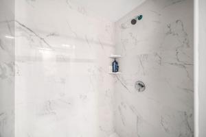 La salle de bains est pourvue d'une douche et de murs en marbre blanc. dans l'établissement 4BR1BTH South Boston Apt perfect for commutes, à Boston