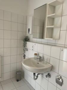La salle de bains est pourvue de carrelage blanc, d'un lavabo et d'un miroir. dans l'établissement Ruhig und zentral wohnen! MA3R, à Essen
